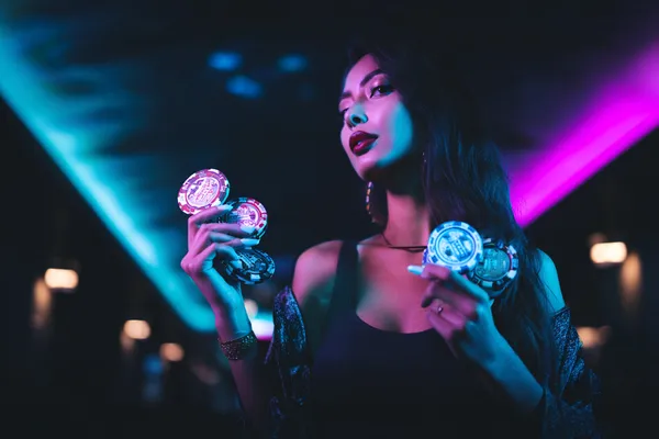 Uma jovem relaxando com o celular enquanto elementos dinâmicos de cassino flutuam ao seu redor, ilustrando a experiência móvel fluida oferecida pelo app 25F.