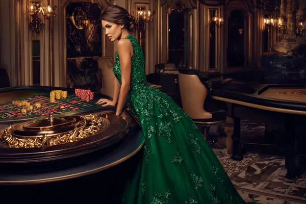Uma mulher em um vestido verde luxuoso ao lado de uma roleta ornamentada, capturando o clima sofisticado do 25F.